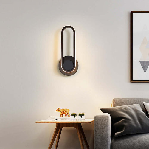 Sleek modern oval wall lamp with warm white light, enhancing a stylish living room setting with high-quality aluminum design.