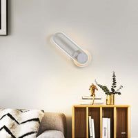 Modern oval wall lamp with sleek design and warm white light illuminating a cozy bedroom setting.